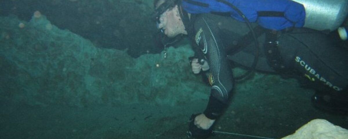 Cavern entrance on Sipadan wall with diver torch illuminating the interior